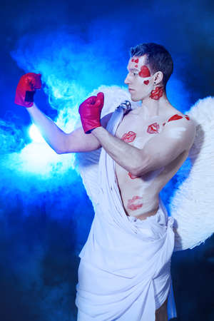 Male angel Cupid covered with kisses wearing boxing gloves. Valentine's day. Love concept.の写真素材