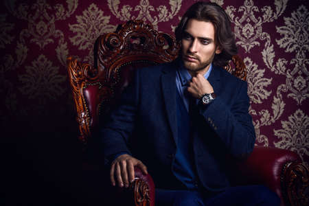 Fashionable male model in elegant formal suit posing in apartments with classical vintage interior.の写真素材