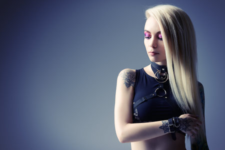Portrait of an extravagant woman with long blonde hair and bright make-up. Rock, punk style. Beauty,...