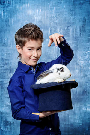 Kid's fashion. Modern nine year old boy posing with rabbit. Clothes for children. Easter holidays.の写真素材