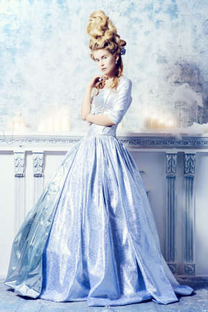 Elegant young woman in a lush white medieval dress with hair in the style of the Renaissance. Beautiful Ice Queen in her snow palace.の写真素材
