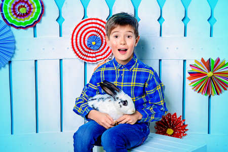 Happy child boy with Easter Bunny in spring decorations. Kid's fashion. Easter holidays.の写真素材