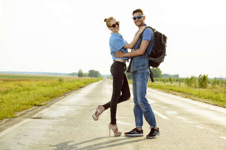Hitchhiking couple. Happy young people standing on a highway.の写真素材