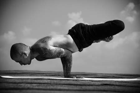 Yoga concept. Experienced yoga master performs various yoga poses on a roof over sky.の写真素材