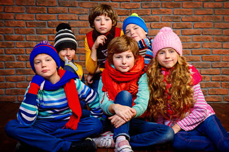 Group of happy joyful children posing together at studio by the brick wall. Kid's fashion. Winter clothes.の写真素材