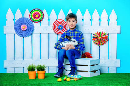 Happy child boy with Easter Bunny and painted eggs in spring decorations. Kid's fashion. Easter holidays.の写真素材