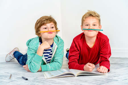 Joyful laughing children reading a book together. Children's fashion. Education. Happiness, activity and child concept. Copy space.の写真素材