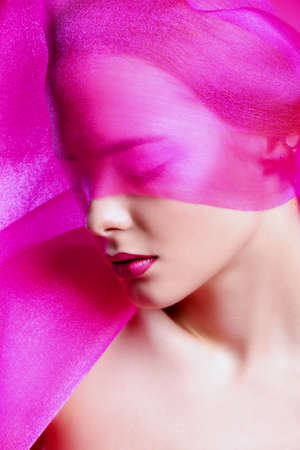 Beauty and cosmetics concept. Beautiful young woman with perfect smooth skin and cherry lips posing with lightweight translucent fabric. Skincare, bodycare.の写真素材