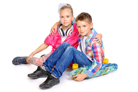 Two beautiful smiling children, a boy and a girl posing together in bright clothes. Children's fashion. Isolated over white background.の写真素材
