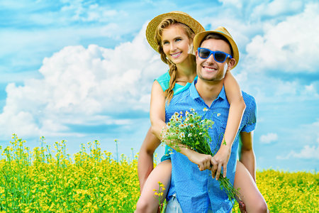 Happy young people in love on a meadow on a sunny summer day. Summer holidays. Love concept.