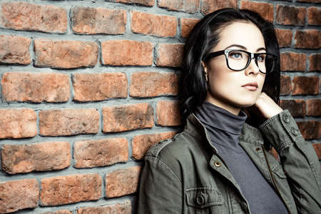 Young woman in glasses standing by the brick wall. Business casual style. Optics.の写真素材