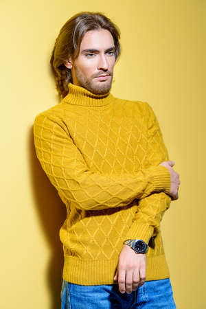 Handsome man wearing yellow pullover. Men's beauty, fashion. Hairstyle for men. Yellow background.の写真素材