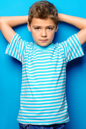 Portrait of a cute boy over bright blue background. Clothes for children. Kid's fashion.