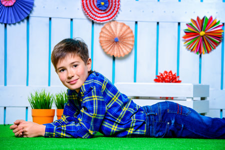 Happy child boy lying on a grass in spring garden decoration. Kid's fashion. Easter holidays.