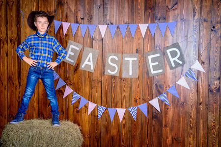 Portrait of a cute nine year old boy posing in Easter decorations. Western style, cowboy. Kid's...