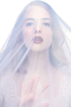 Close-up portrait of a beautiful girl wearing a veil. Beautiful tender bride woman. Fashion shot.の写真素材