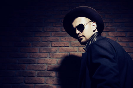 Portrait of a stylish handsome man wearing hat, coat and sunglasses. Men's beauty, seasonal fashion....