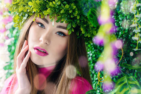 Spring girl portrait. Tender young woman in a wreath of green plants. Beauty, fashion concept. Cosmetics and perfumery.の写真素材