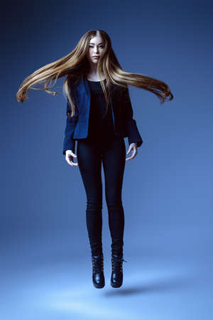Vogue shot. Full length portrait of a fashionable model with beautiful long hair posing at studio in a motion.の写真素材