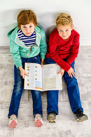 Two funny children reading book together. Educational concept.の写真素材
