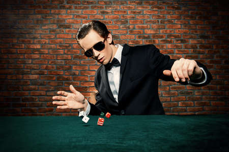 Excited gambling man throwing dice on a game table in a casino. Gambling, playing cards and roulette.の写真素材