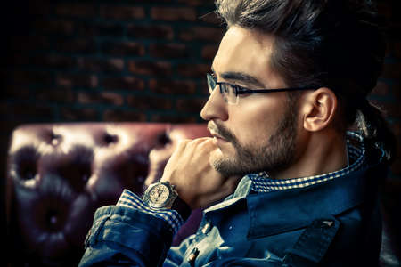 Portrait of a well-dressed imposing man in elegant glasses posing in apartments with luxurious classic interior. Men's beauty, fashion. Hair styling, barbershop.の写真素材