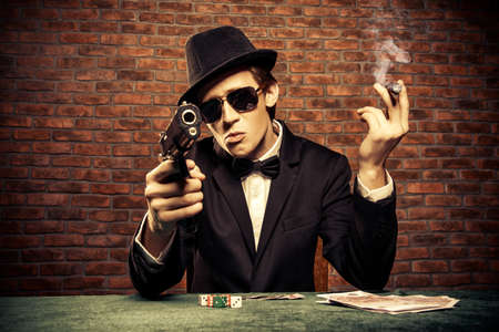 Cool gangster with a bunch of money threatens gun. Gambling industry, casino. Underworld concept.の写真素材