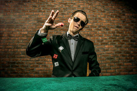 Excited gambling man throwing dice on a game table in a casino. Gambling, playing cards and roulette.の写真素材