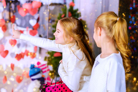 Two cute little girls looking at the shop window. Shopping concept. Kid's fashion. Modern children. Seasonal sale, shopping.の写真素材