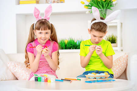Happy children painting eggs for Easter at home.の写真素材
