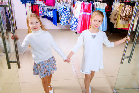 Two cute little girls go shopping. Kid's fashion. Modern children. Seasonal sale, shopping.の写真素材