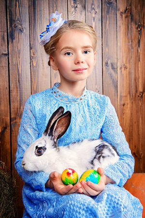Easter holidays. Happy little child girl holds Easter Bunny and painted eggs and smiling.