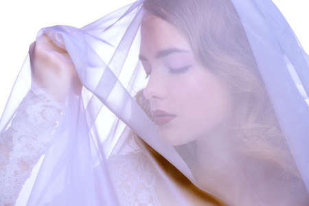 Close-up portrait of a beautiful girl wearing a veil. Beautiful tender bride woman. Fashion shot.の写真素材