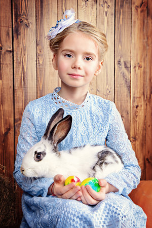 Easter holidays. Happy little child girl holds Easter Bunny and painted eggs and smiling.