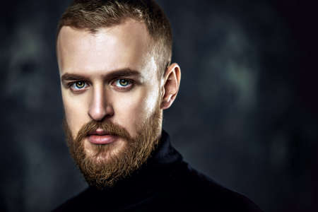 Close-up portrait of a modern young man in black clothes over grunge background. Men's beauty, fashion.の写真素材
