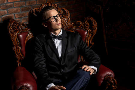 Portrait of an imposing well dressed man sitting in a classic luxurious armchair. Luxury. Men's beauty, fashion.の写真素材