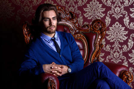 Fashionable male model in elegant formal suit posing in apartments with classical vintage interior.の写真素材