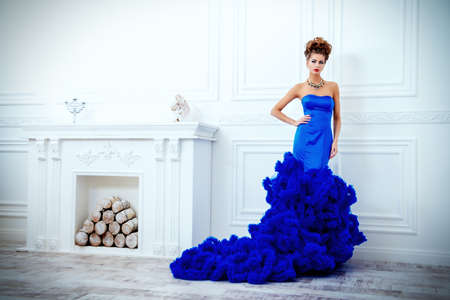 Full length portrait of a stunning young woman wearing luxurious long dress and jewellery. Luxury, rich lifestyle. Jewellery. Fashion shot. Interior in classical style.の写真素材