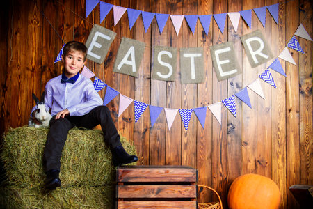 Easter holidays. Happy child boy sitting on a haystack with Easter Bunny.の写真素材