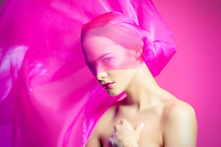 Beauty and cosmetics concept. Beautiful young woman with perfect smooth skin and cherry lips posing with lightweight translucent fabric. Skincare, bodycare.の写真素材