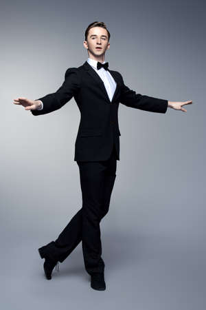Elegant young man dancer in black suit and bow-tie posing at studio. Male ballet dancer.の写真素材