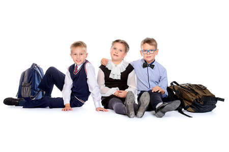 Portrait of three happy school friends posing together at studio. School uniform. Education. Isolated over white.の写真素材