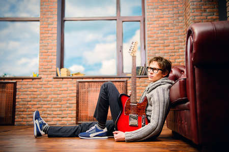 Handsome young man musician playing his guitar at home or studio. Musical concept. Electric guitar.の写真素材