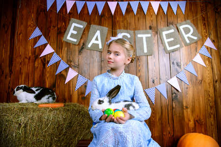 Easter holidays. Happy little child girl holds Easter Bunny and painted eggs and smiling.の写真素材