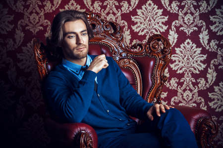 Fashionable male model in elegant classical clothes posing in apartments with classical vintage interior.の写真素材