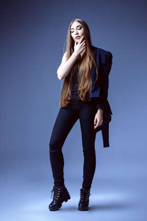 Vogue shot. Full length portrait of a fashionable model with beautiful long hair posing at studio in casual black clothes.の写真素材