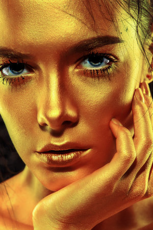 Beauty concept. Close-up portrait of a beautiful young woman with glowing golden skin. Skin care...