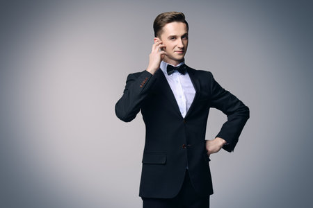 Portrait of a handsome young man in elegant black suit and a bow-tie. Male beauty, fashion. Studio shot.の写真素材