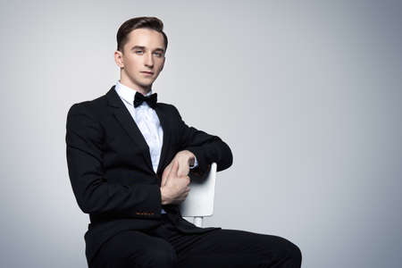Portrait of a handsome young man in elegant black suit and a bow-tie. Male beauty, fashion. Studio shot.の写真素材