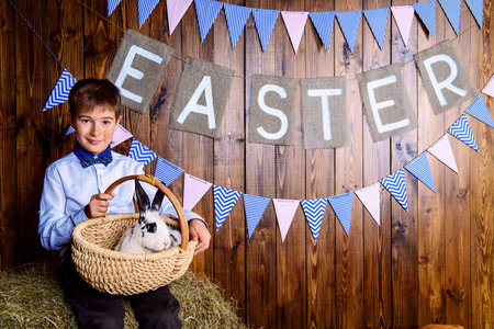 Easter holidays. Happy child boy sitting on a haystack with Easter Bunny.